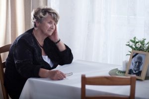 Woman sitting at a table grieving her dead husband