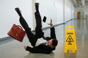 Man slipping on a wet floor next to a wet floor sign.