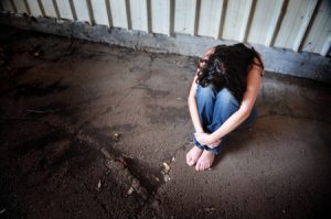 Woman sitting curled up on the ground