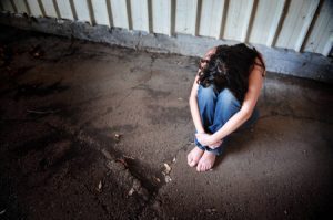 Woman sitting curled up on the ground