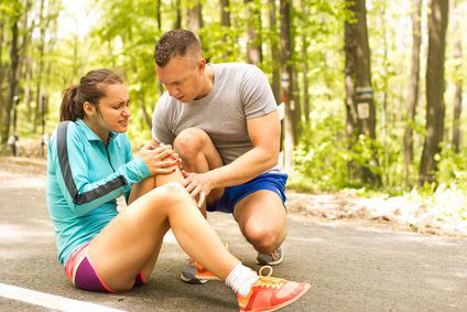 Man helps woman with knee injury in a park