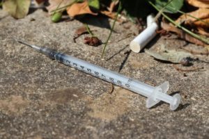 Needle and a cigarette laying on a footpath