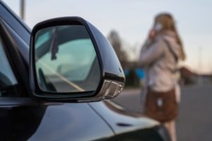 a young woman on the phone walking in front of a car