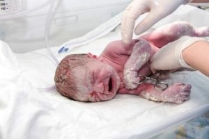 Newborn baby in hospital being handled by medical professional. 