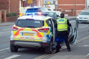 A policeman getting in the car ready to go to the scene of a fatal road traffic accident