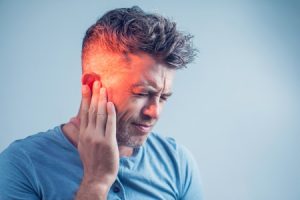 Man putting his hand on his ear after an ear injury