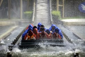 A water raft ride and waterslide with a raft of people at the bottom.