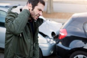 Man holds neck due to neck injury from a roundabout accident