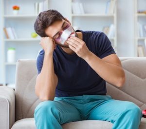 Man sitting on a couch with a bandage across the injury on his face