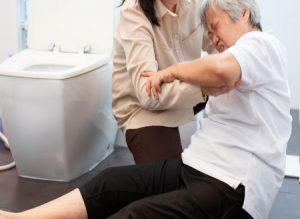 Old woman who slipped in a toilet being helped up by a younger woman