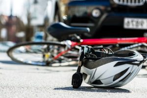 helmet laying on the floor next to a bicycle after a collision with a car