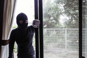 Man wearing a balaclava breaking into a home ready to commit a robbery