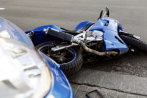 Motorcycle laying on the ground after a crash with a car