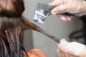 A hair dresser applying hair dye for a client