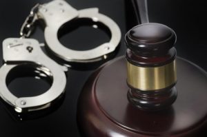 A pair of handcuffs and a gavel on a desk