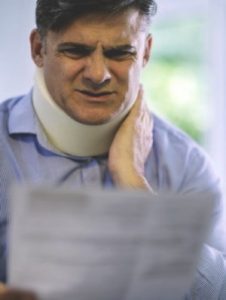 Person looking at a newspaper after hurting their neck in a seatbelt accident