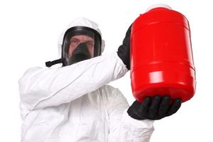Man holding up a canister of hazardous materials in a hazmat suit