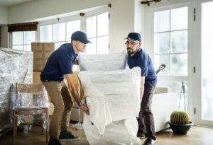 Two men lifting heavy furniture straining their backs