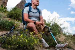 Man with a prosthetic leg in place of a missing limb sitting out in nature