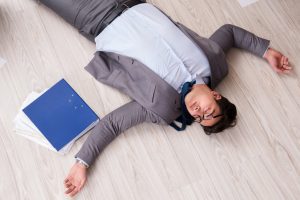 An unconscious man laying on the ground in an office