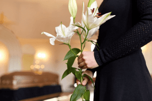 A man holding a lily flower in front of a casket