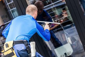Window cleaner in the process of cleaning a window with appropriate safety gear