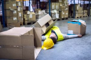 A man injured on the floor surrounded by boxes.