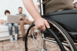 Person attempting to move his wheelchair with his family in the background