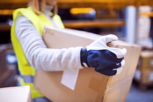 A worker wearing gloves and carrying a box. 