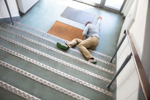 A man lying down at the bottom of some stairs.