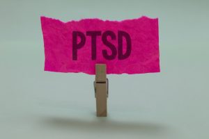 Clothes peg holds pink sign that reads "PTSD".