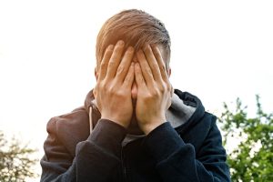 Man with his hands over his face in distress
