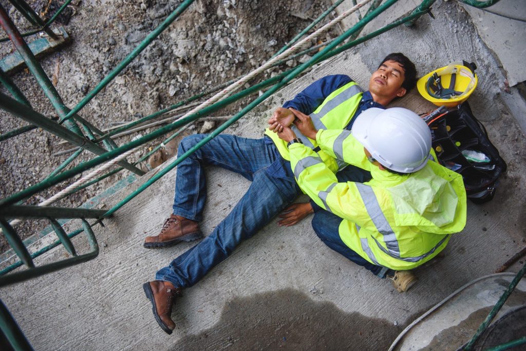 Man on the floor after an accident with a co-worker checking his pulse