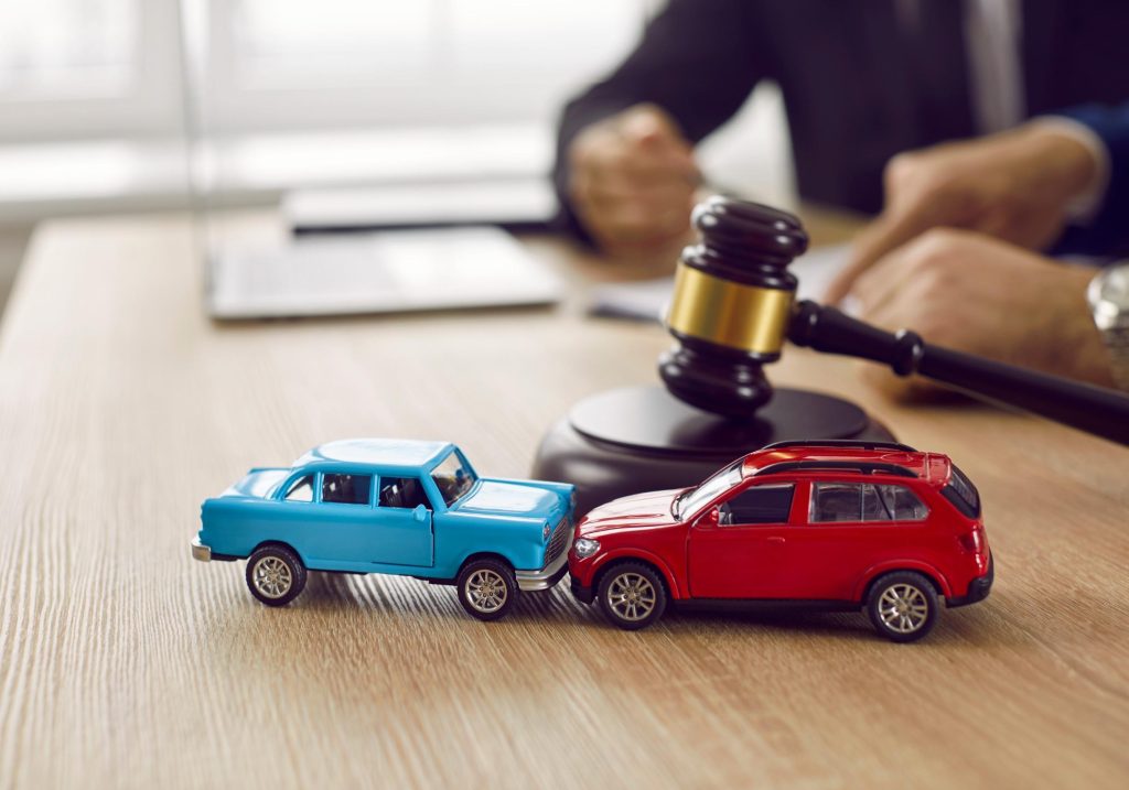 Lawyers discussing an accident claim with two toy cars crashing in the foreground