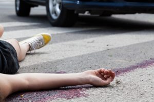 A person who was hit by a car as a pedestrian lays on the road. 