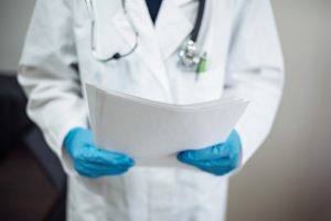 doctor holding a clip board with a stethoscope around his neck for a delayed diagnosis guide