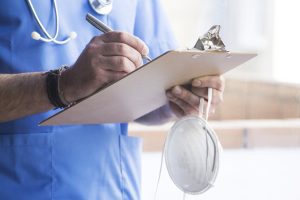 Doctor with mask, stethoscope and reports.