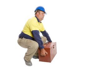 A male worker wearing a blue hard hart lifting a tool box 
