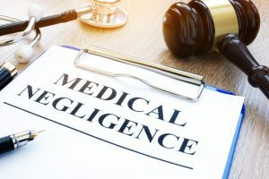 medical negligence written on a blue clipboard next to a stethoscope and agavel hammer