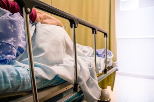 hospital bed with side up showing a ladies right arm. 