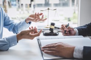 A specialist medical negligence solicitor discussing with their client at a desk with a set of scales and a gavel hammer