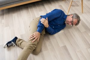 A man, who has fallen on the ground, holding his leg and elbow in pain