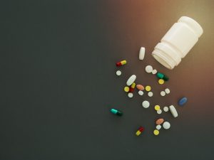 A spilled bottle with pills spread across a table. Providing the wrong medication through an avoidable error is an example of pharmacist negligence.