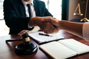 A data breach solicitor shaking hands across a desk with a gavel and open notebook.