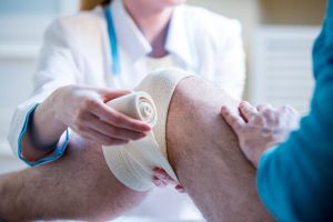 A doctor ensuring adequate patient hygiene by changing their leg dressing.