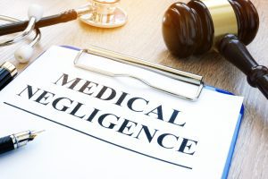 A clipboard holding a sheet of paper that has the words "Medical Negligence" written on it.