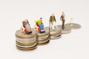 Miniature injured people placed on top of stacks of coins.