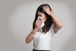 Woman feeling ill and blowing nose due to allergic reaction