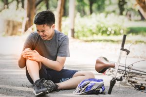 A man holding his knee in pain after a bike accident.