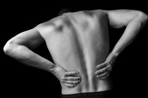 A person is bent over holding their lower back.
